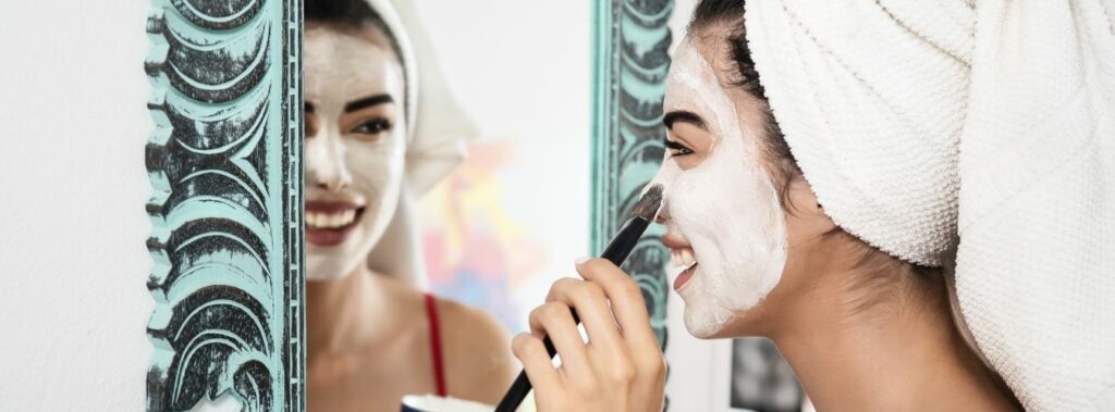 Woman Applying Mask on her Face with Brush & Looking at Mirror | Isya Aesthetics in Vasant Vihar, New Delhi