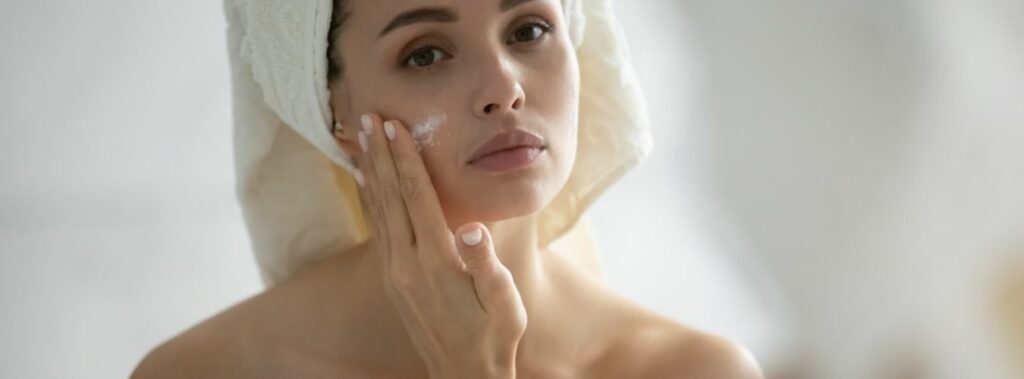 Towel Wrapped Hair Woman Applying Cream on her Face | Isya Aesthetics in Vasant Vihar, New Delhi